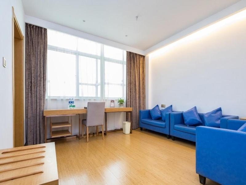 Una sala de estar con un sofá azul y una mesa. en GreenTree Inn Changzhou Xixiasu Town Express Hotel, en Luoxi