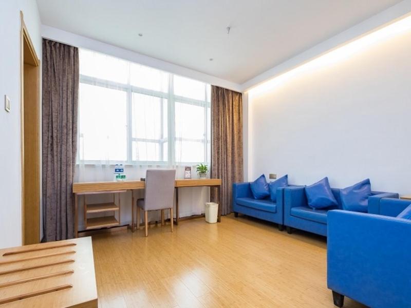 a living room with a blue couch and a table at GreenTree Inn Changzhou Xixiasu Town Express Hotel in Luoxi