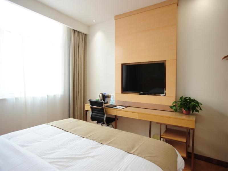 Habitación de hotel con cama y escritorio con TV. en GreenTree Inn Baoding Qingyuan District Jianshe North Road Express Hotel en Baoding