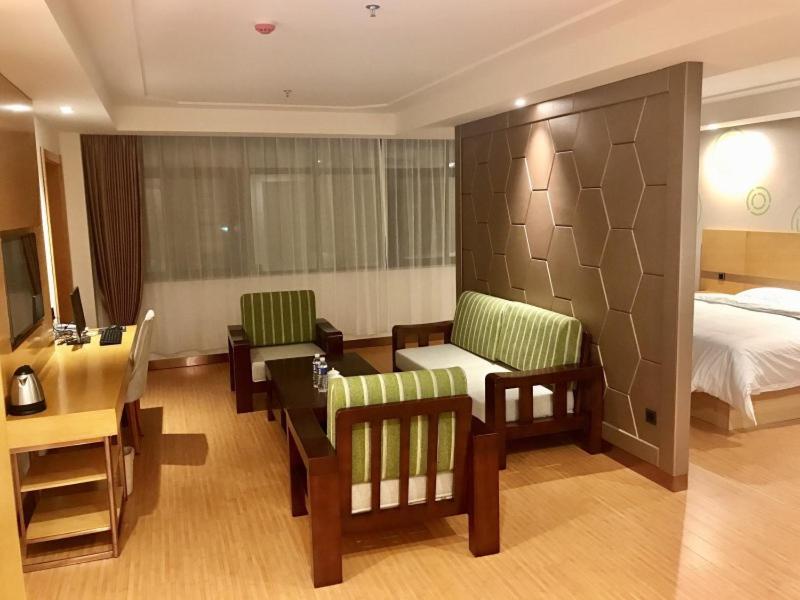 a hotel room with a bed and a table and chairs at GreenTree Inn LuoYang Ruyang County Dujuan Avenue Hotel in Ruyang