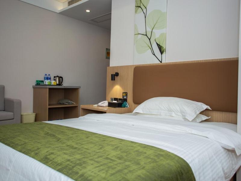 a bedroom with a large bed with a green blanket at GreenTree Inn Lu'an Kaihong Plaza Express Hotel in Lu'an