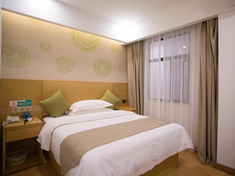 a bedroom with a large bed and a window at GreenTree Inn Huai Nan Shou County Zijin Road Express Hotel in Majiaxu
