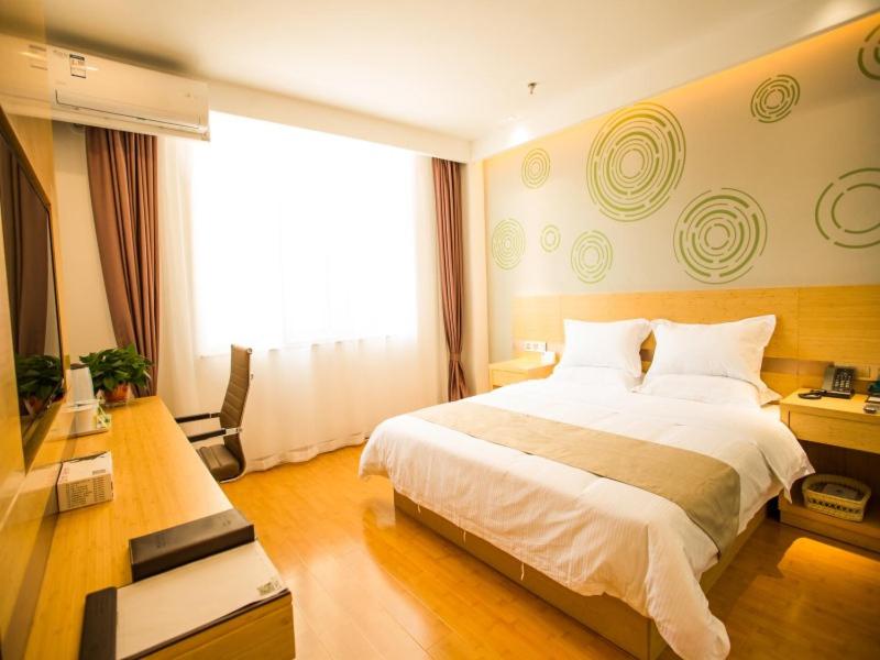 a hotel room with a large bed and a television at GreenTree Inn Jinzhong Yuci Old Town Express Hotel in Jinzhong