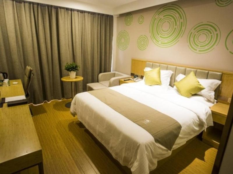 una habitación de hotel con una cama grande con almohadas amarillas en GreenTree Inn Xingtai Julu County Fengqing Road Business Hotel, en Xingtai