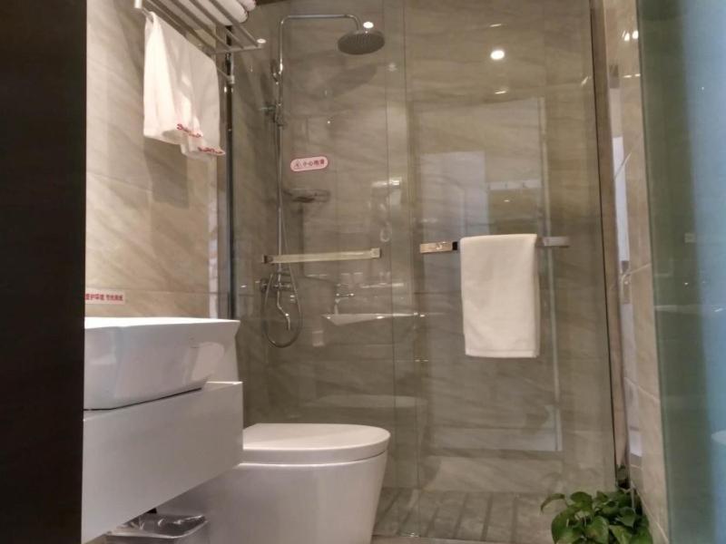 uma casa de banho com um chuveiro, um WC e um lavatório. em Shell Shanghai New International Expo Center Fanghua Road Metro Station Hotel em Xangai