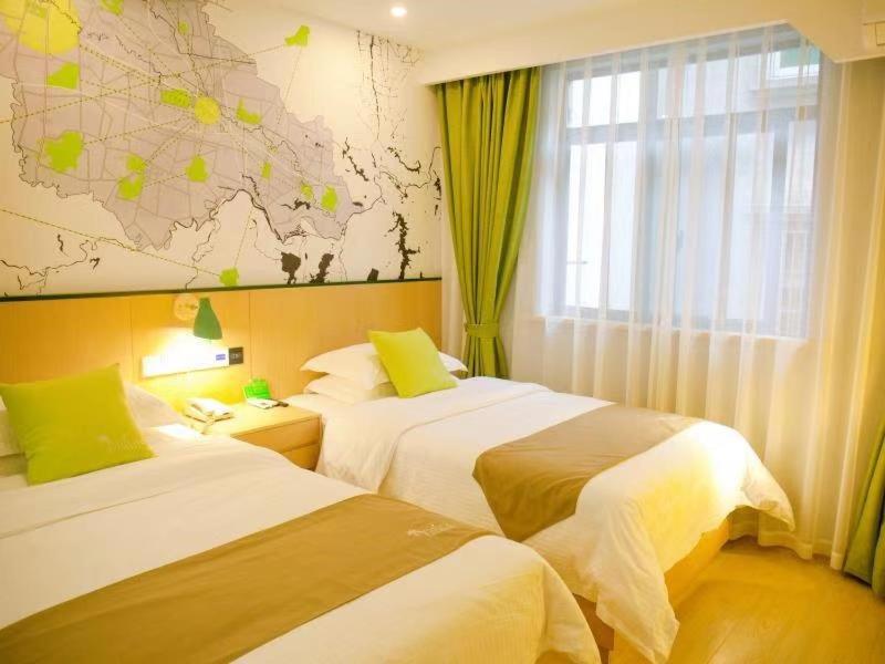 two beds in a hotel room with a map on the wall at Vatica Fuyang Linquan County Jiangziya Square Hotel in Fuyang