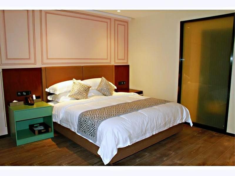 a bedroom with a large bed with a wooden headboard at GME Huainan Tianjiaan District Chaoyang East Road Hotel in Huainan