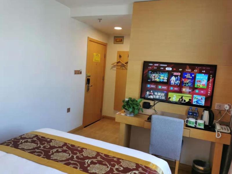 een kamer met een bed en een bureau met een monitor bij GreenTree Xining Chengzhong Area Dongguan Street Street Hotel in Xining