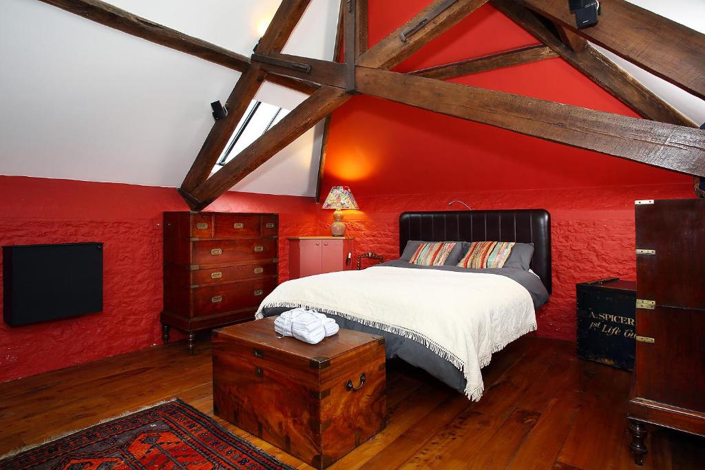1 dormitorio con paredes rojas, 1 cama y TV en Snobs and Rebels Apartments, en Shaftesbury