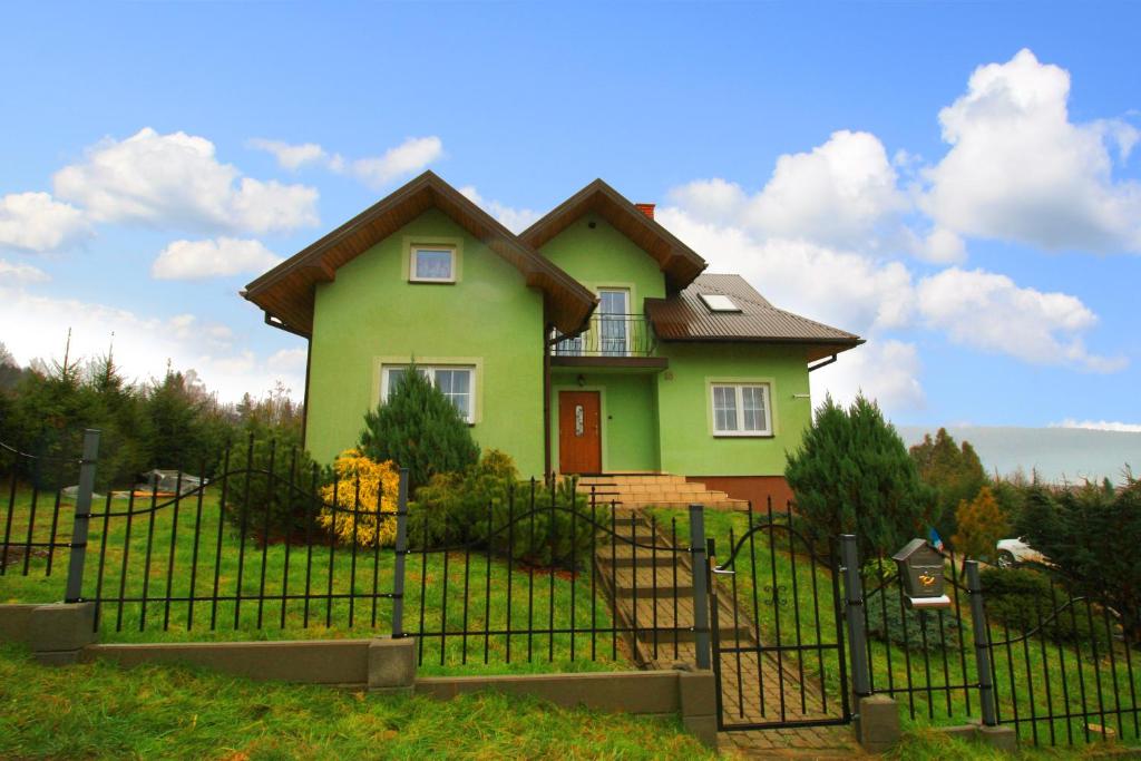 uma casa verde numa colina atrás de uma cerca em Przystań Laworta em Ustrzyki Dolne