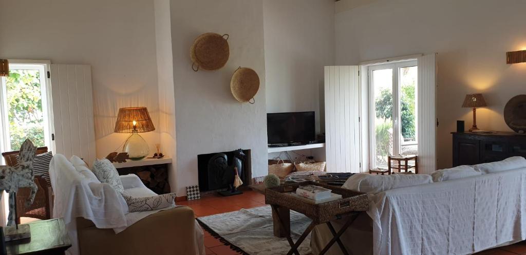 a living room with white furniture and a fireplace at Comporta House in Comporta
