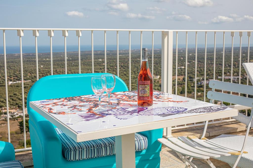 a bottle of wine and glasses on a table on a balcony at Dimore del TEMPO PERS0 Mare videre in Ostuni