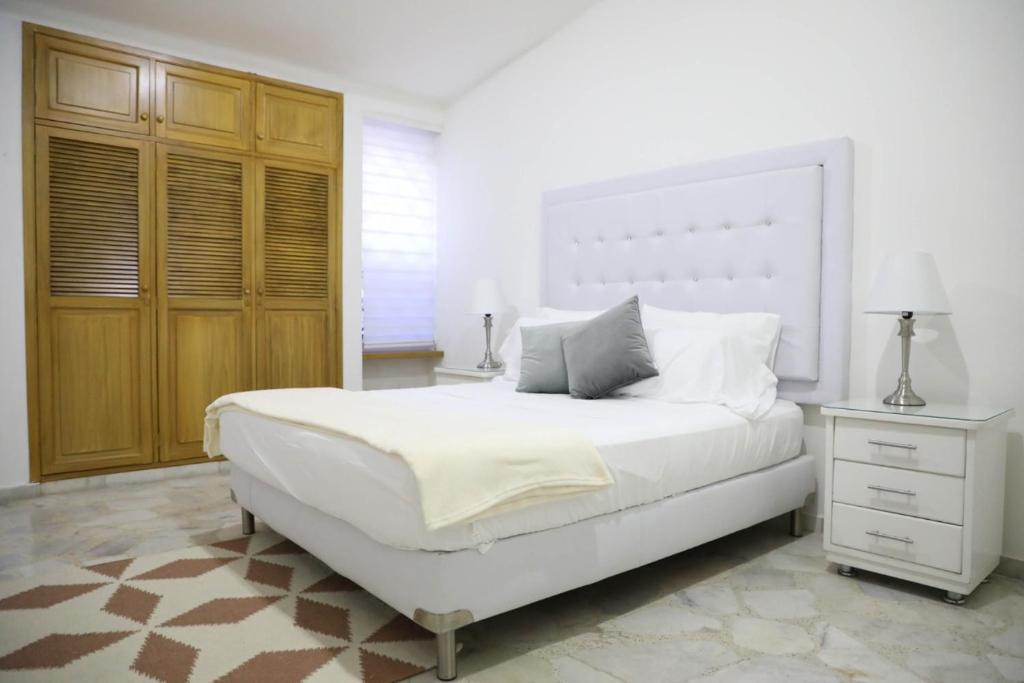 a white bedroom with a large bed and a dresser at HOTEL BELEN-La Flora- Cali Valle del Cauca in Cali