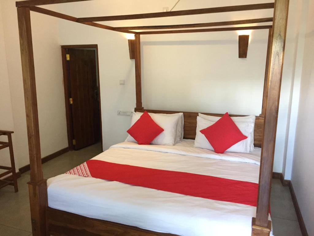 a bedroom with a bed with red and white pillows at Heavens Holiday Resort in Kandy