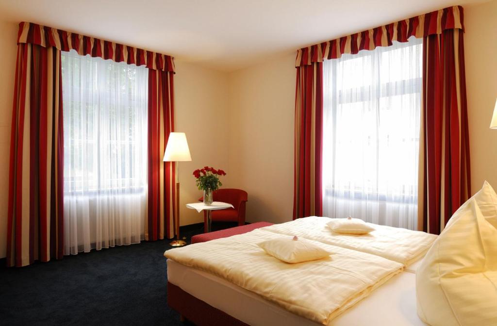 シュヴァインフルトにあるAlte Reichsbankのベッド1台と窓2つが備わるホテルルームです。