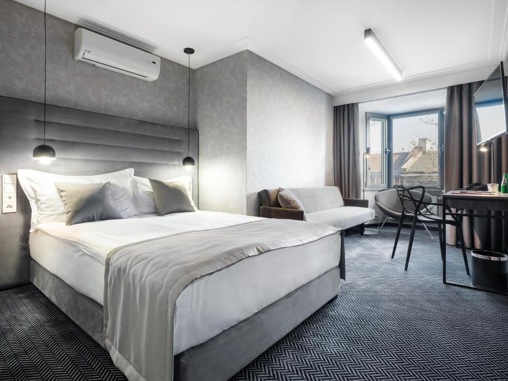 a hotel room with a large bed and a desk at Hotel Logos Kraków in Krakow