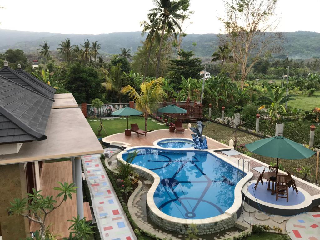 eine Aussicht über einen Pool mit Tischen und Sonnenschirmen in der Unterkunft Villa Umah Didua in Lovina
