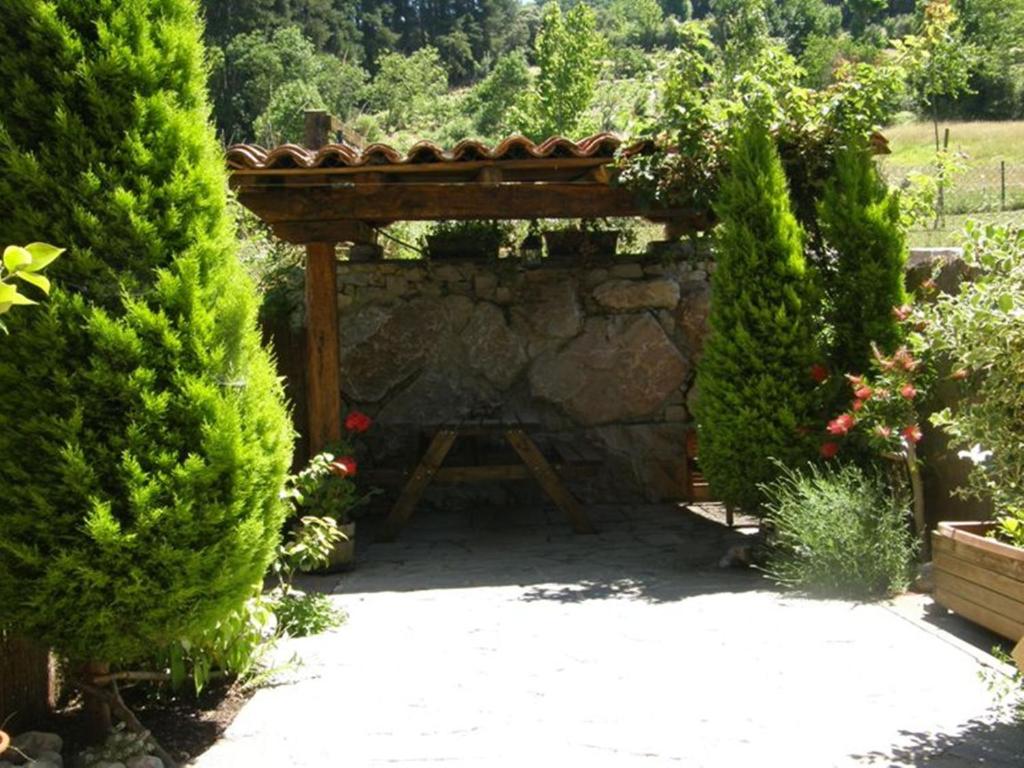 una chimenea de piedra en un jardín con estructura de madera en Chalet Rural El Encanto, en Ojedo