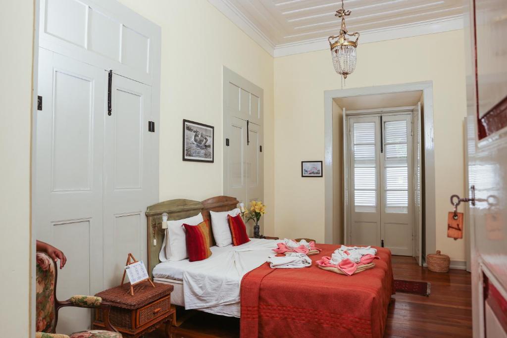 a bedroom with a bed with a red blanket at The Colonial Guest House in São Filipe