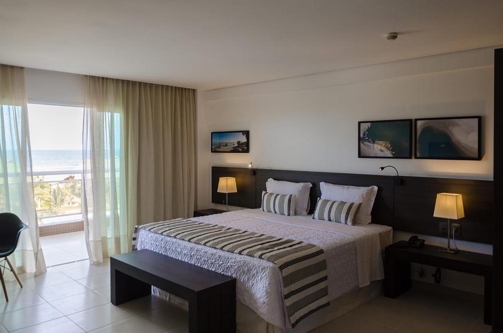 een slaapkamer met een bed en uitzicht op de oceaan bij Crocobeach Hotel in Fortaleza