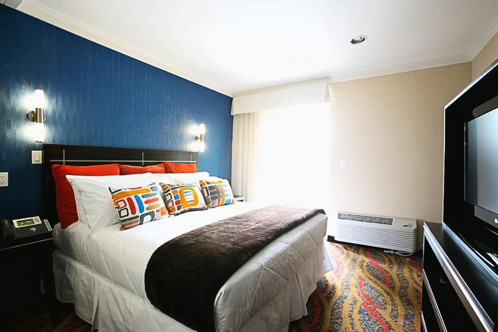 a bedroom with a large bed and a flat screen tv at Nesva Hotel - New York City Vista in Queens