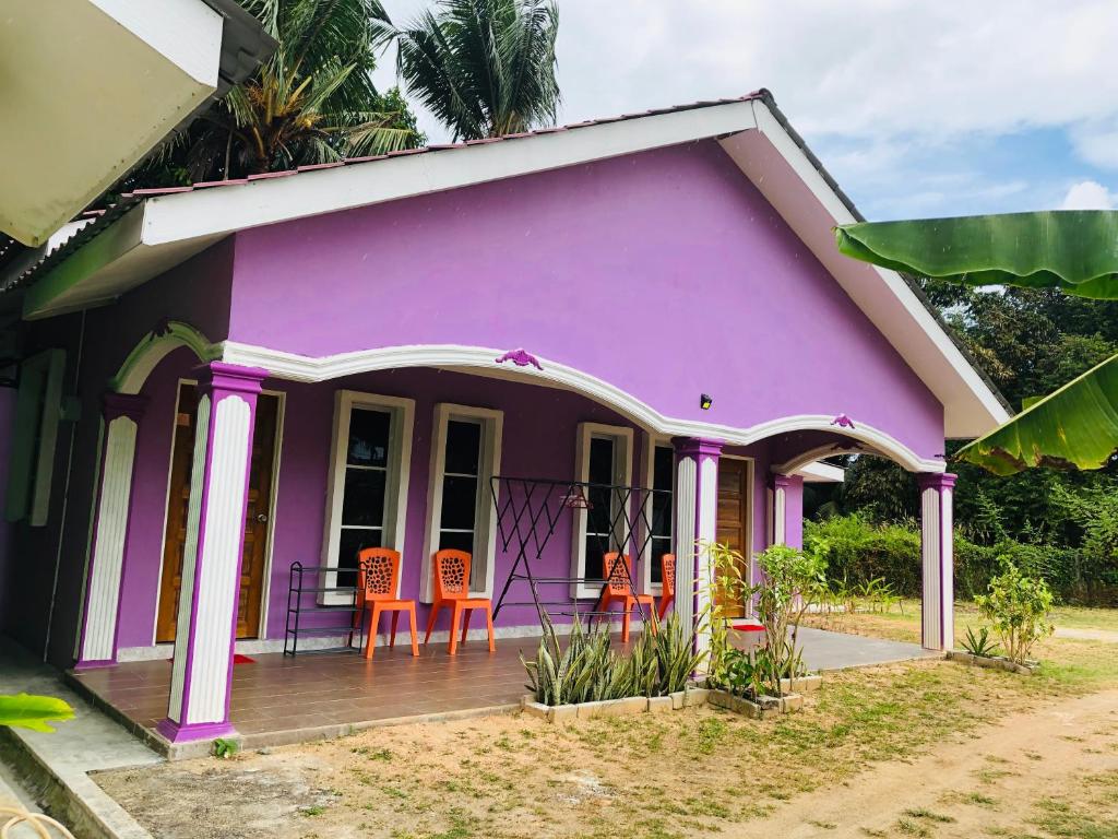 a pink house with orange chairs in front of it at D'BERJAYA HOMESTAY & ROOMSTAY in Pantai Cenang