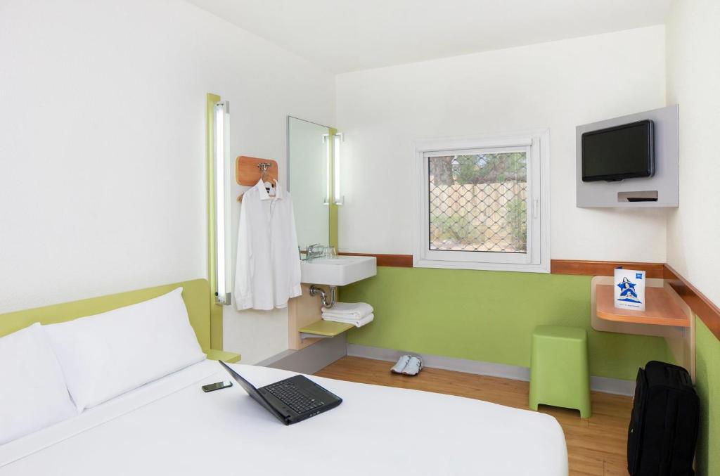 a bedroom with a bed with a laptop on it at ibis Budget - Melbourne Airport in Melbourne