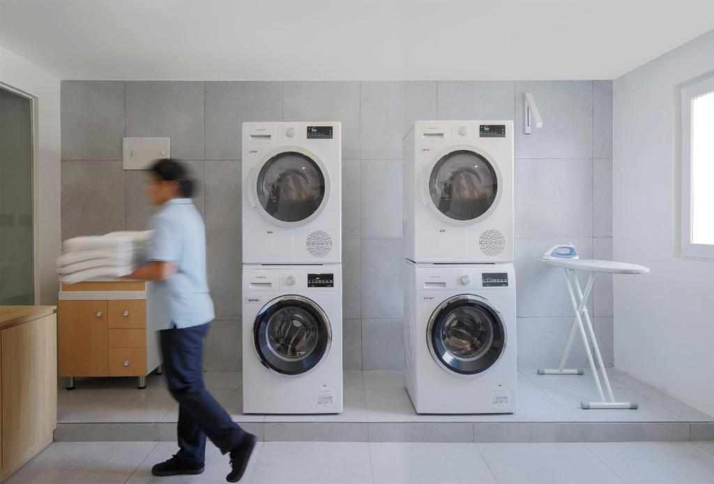 a woman walking past three washing machines in a bathroom at Holiday Inn Express Pune Pimpri, an IHG Hotel in Pune