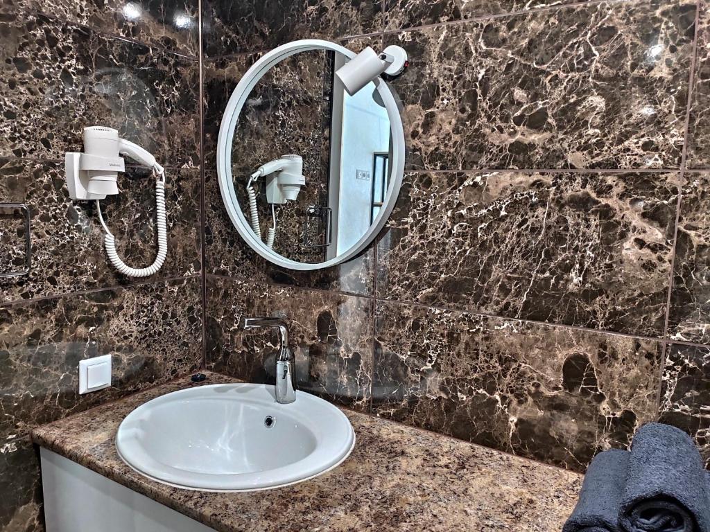 W łazience znajduje się umywalka i lustro. w obiekcie Loft возле парка, стадиона и озера w Iwano-Frankiwsku