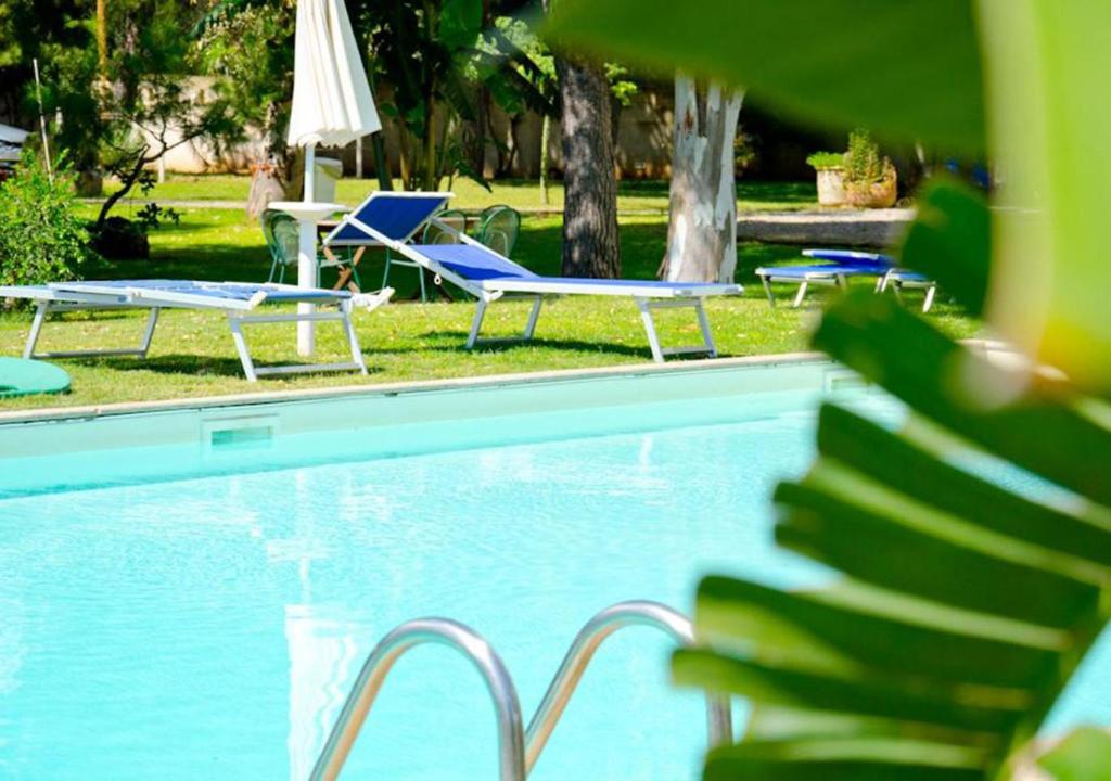 una piscina con 2 tumbonas y una mesa en Fuori Rotta Holiday Home en Maruggio