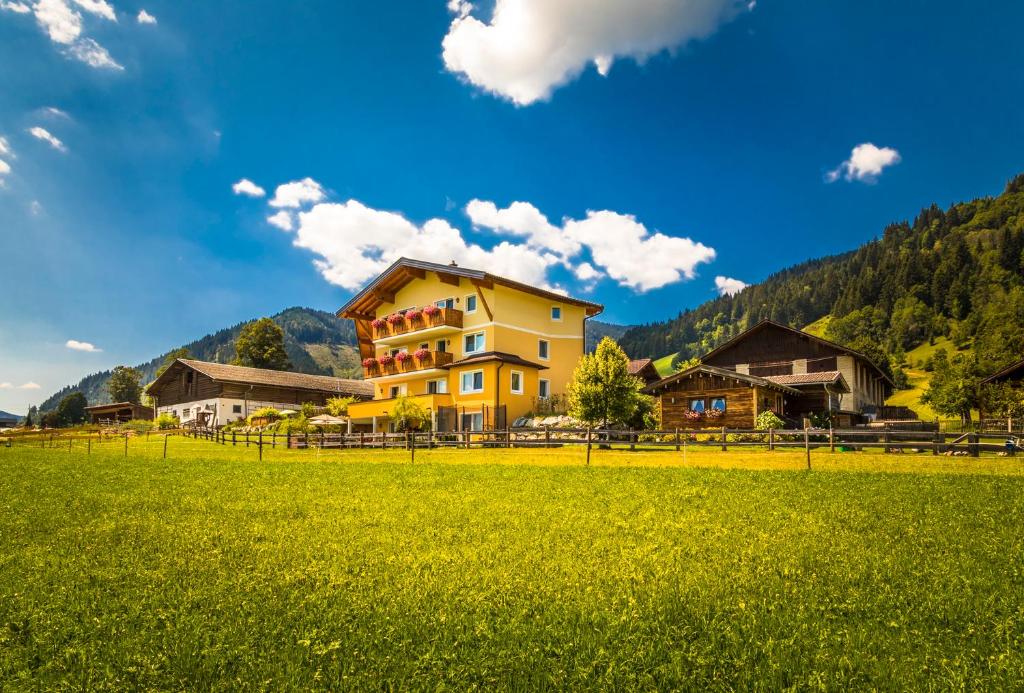 une maison jaune dans un champ d'herbe verte dans l'établissement Ferienhof Unterlehengut, à Flachau