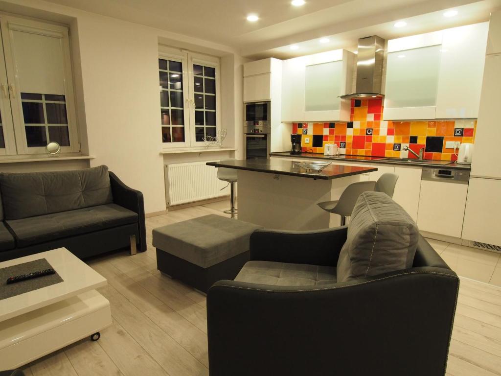 a living room with a couch and a kitchen at Grand-Tourist Amber Center Apartments in Gdańsk