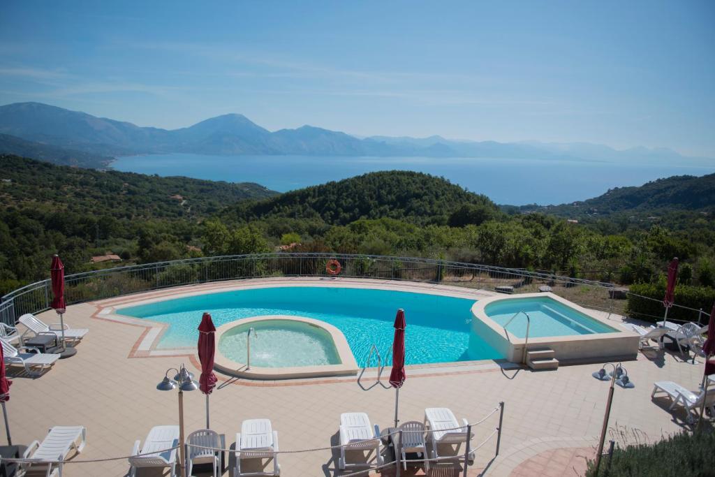 einen Pool mit Stühlen und Blick auf das Wasser in der Unterkunft Hotel Caluna Charme in San Giovanni a Piro