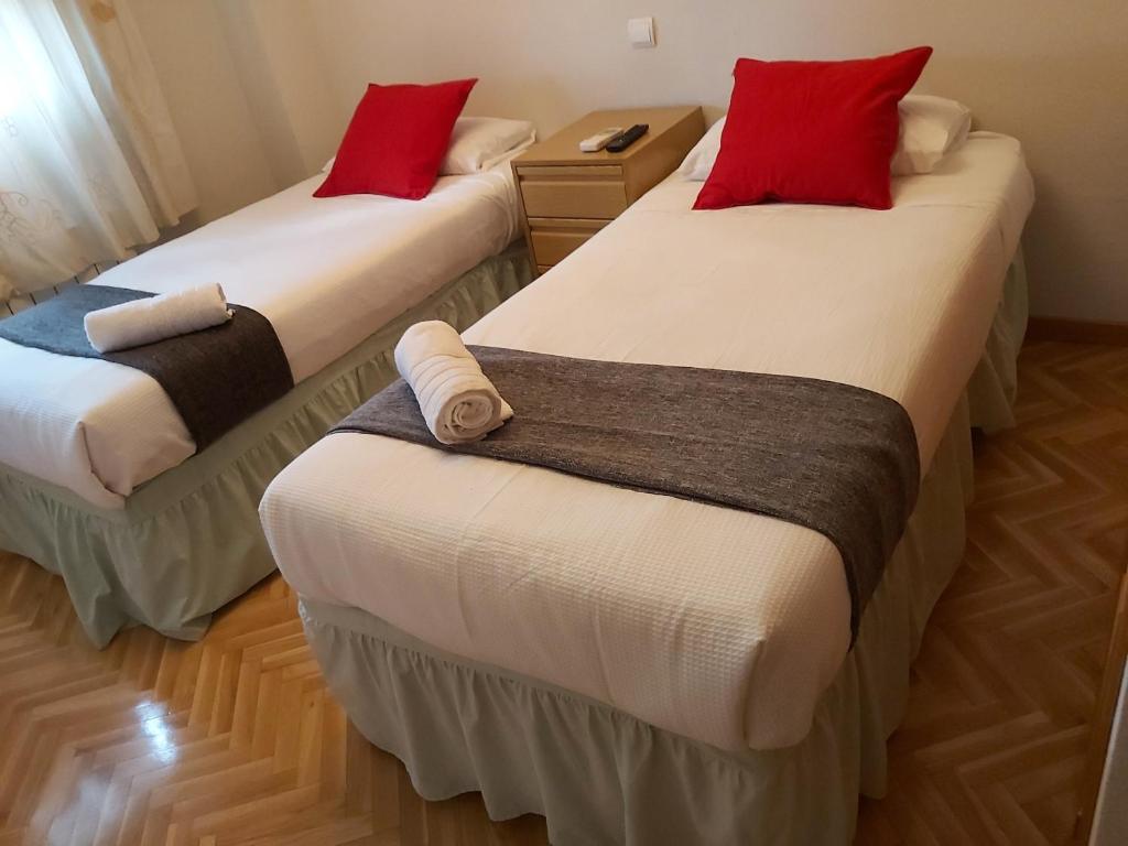 Habitación con 2 camas y almohadas rojas. en Chalet Avila Rooms, en Madrid