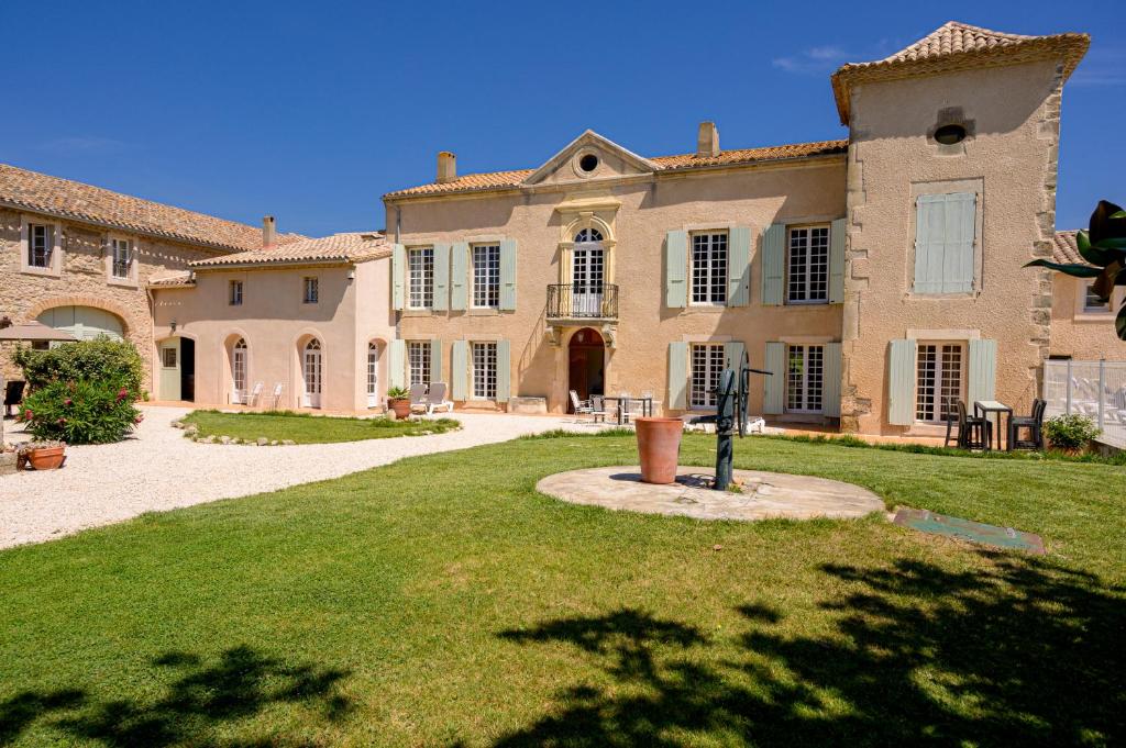 une grande maison avec une cour en gazon devant elle dans l'établissement Domaine de Puychêne, à Saint-Nazaire-dʼAude