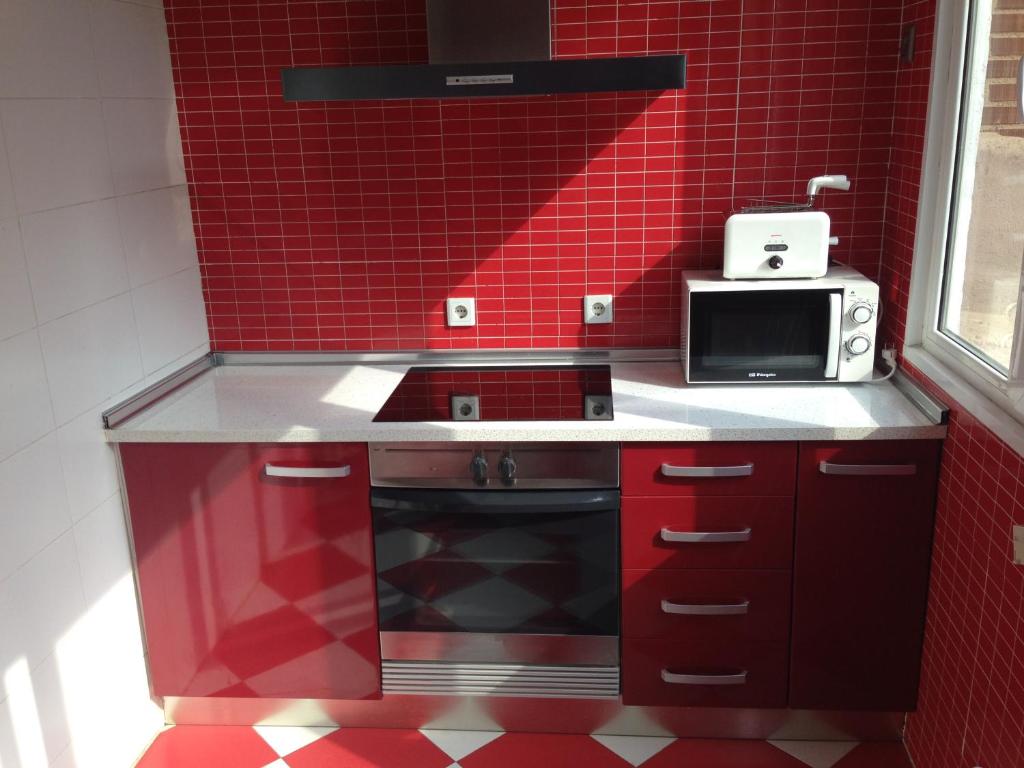 a red kitchen with a stove and a microwave at ap. con encanto in Haro
