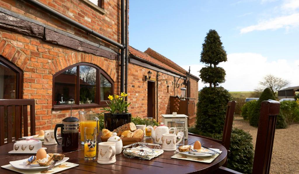 a wooden table with food on it in front of a brick building at Humble Bee Cottage in Folkton