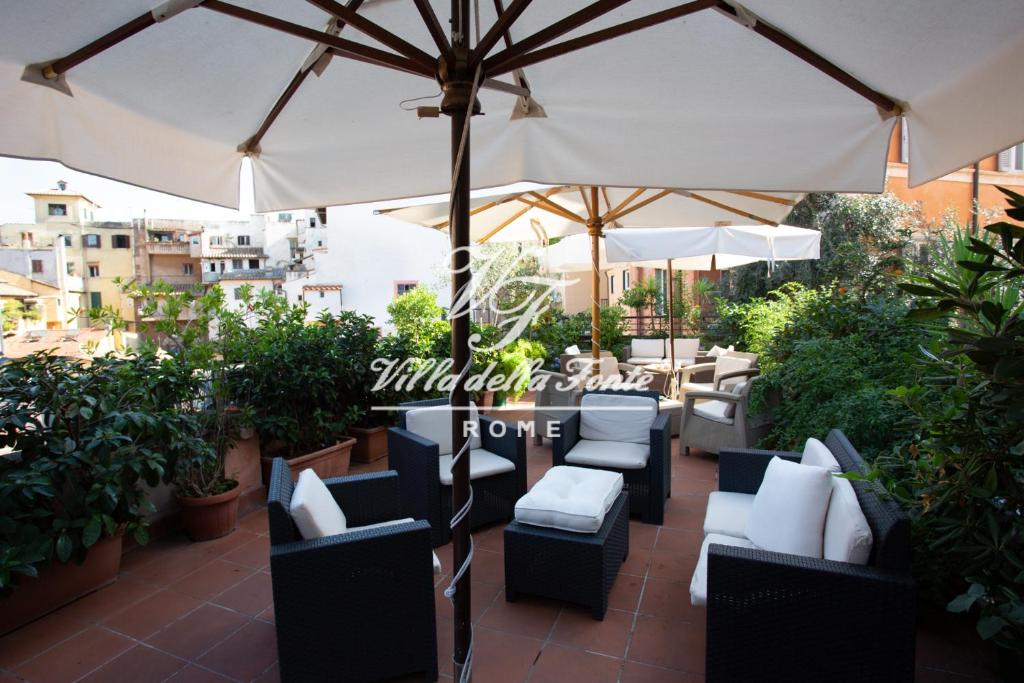 a patio with tables and chairs and an umbrella at Villa della Fonte in Rome