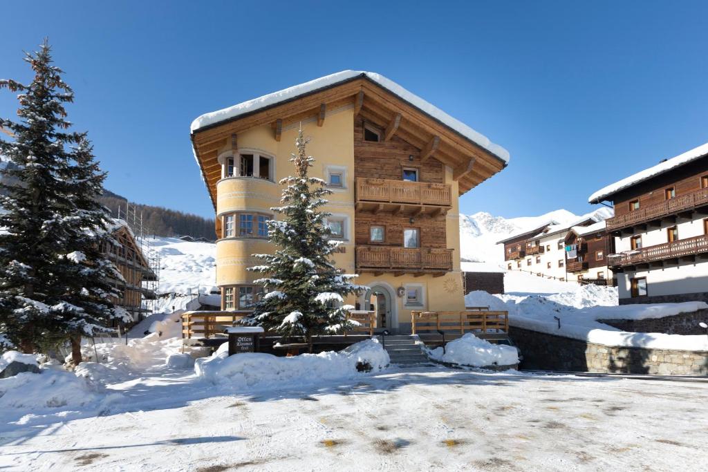 un grande edificio con neve sul terreno di fronte ad esso di Hotel "La Suisse" a Livigno