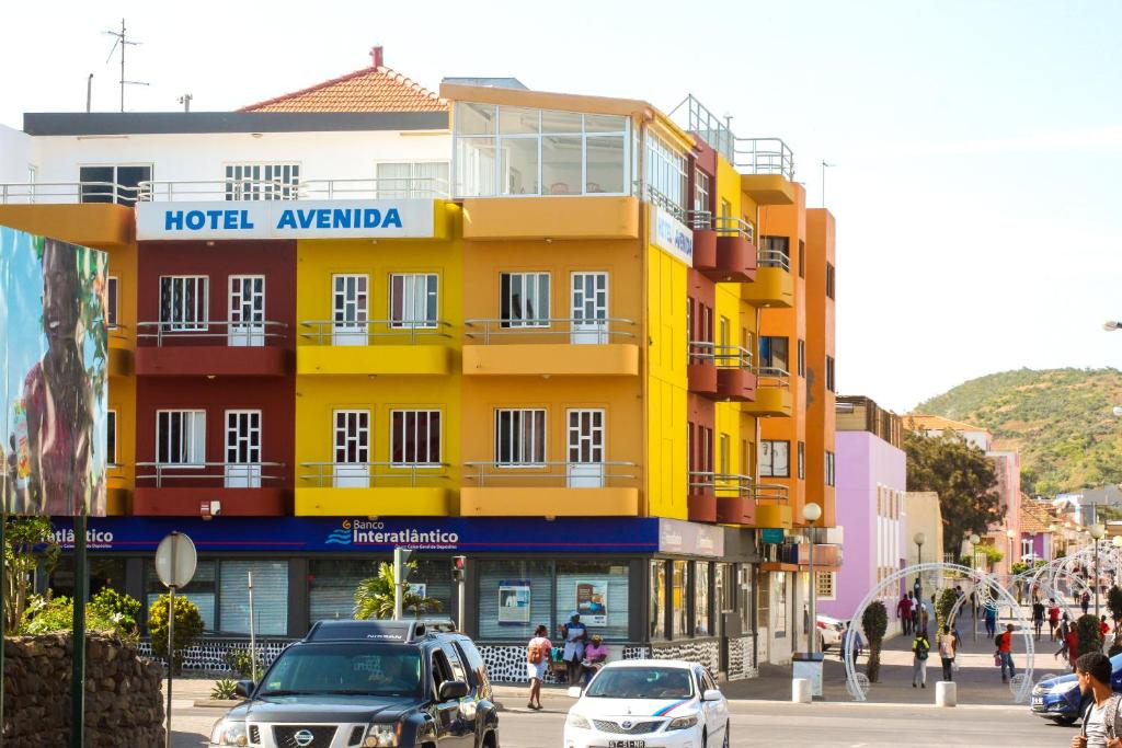 een geel gebouw in een stadsstraat met auto's bij Hotel Avenida in Assomada