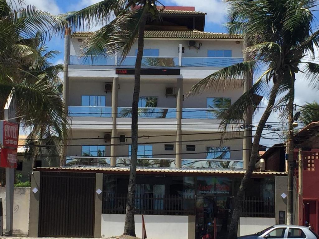 a building with palm trees in front of it at Hotel Lazer Piata in Salvador