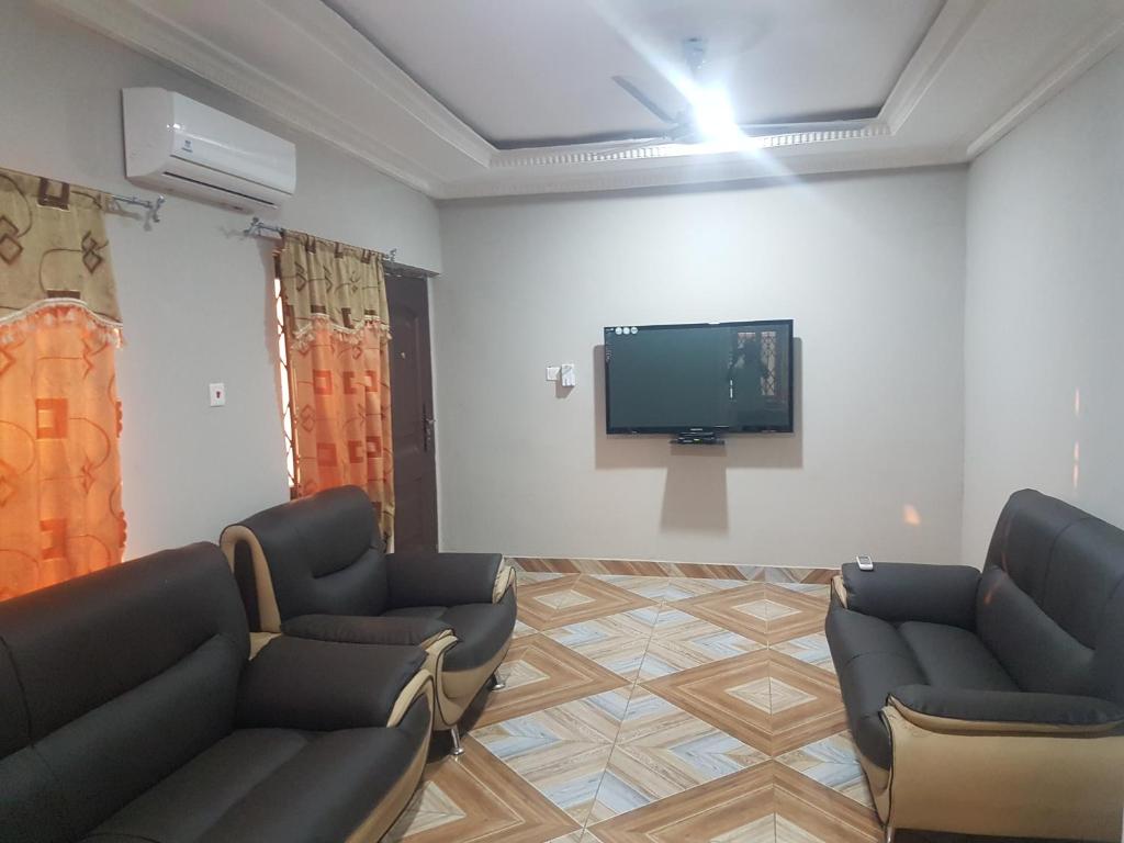 una sala de espera con sofás y TV de pantalla plana. en Private Executive Apartments en Accra