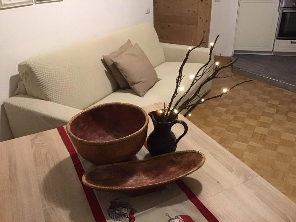 a bowl and a vase on a table with a couch at Un nido in centro in Madesimo