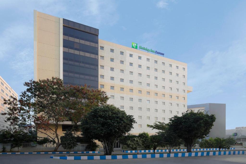 un grand bâtiment blanc avec des arbres devant lui dans l'établissement Holiday Inn Express Hyderabad HITEC City, an IHG Hotel, à Hyderabad