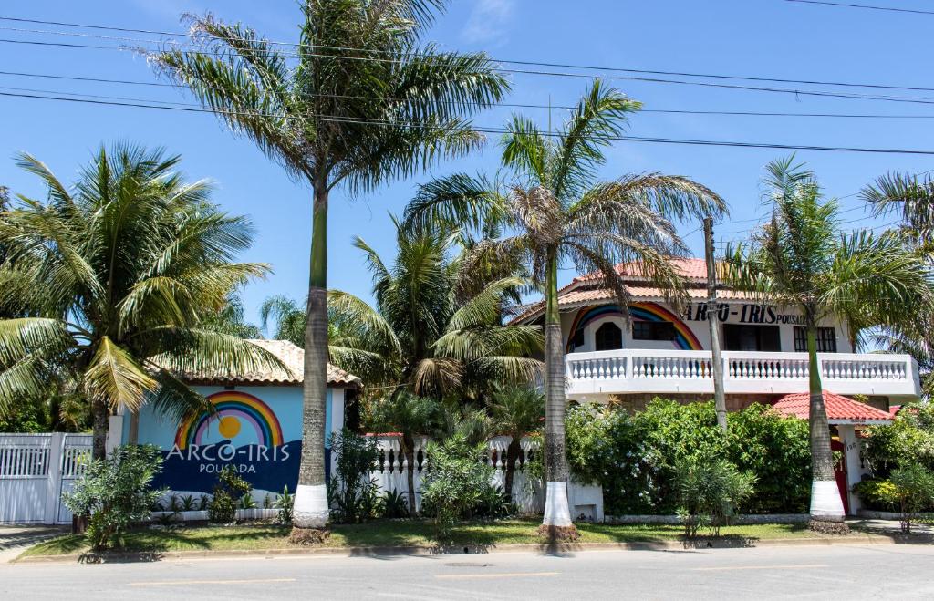 una casa con palmeras delante en Arco Íris Pousada, en Ilha Comprida
