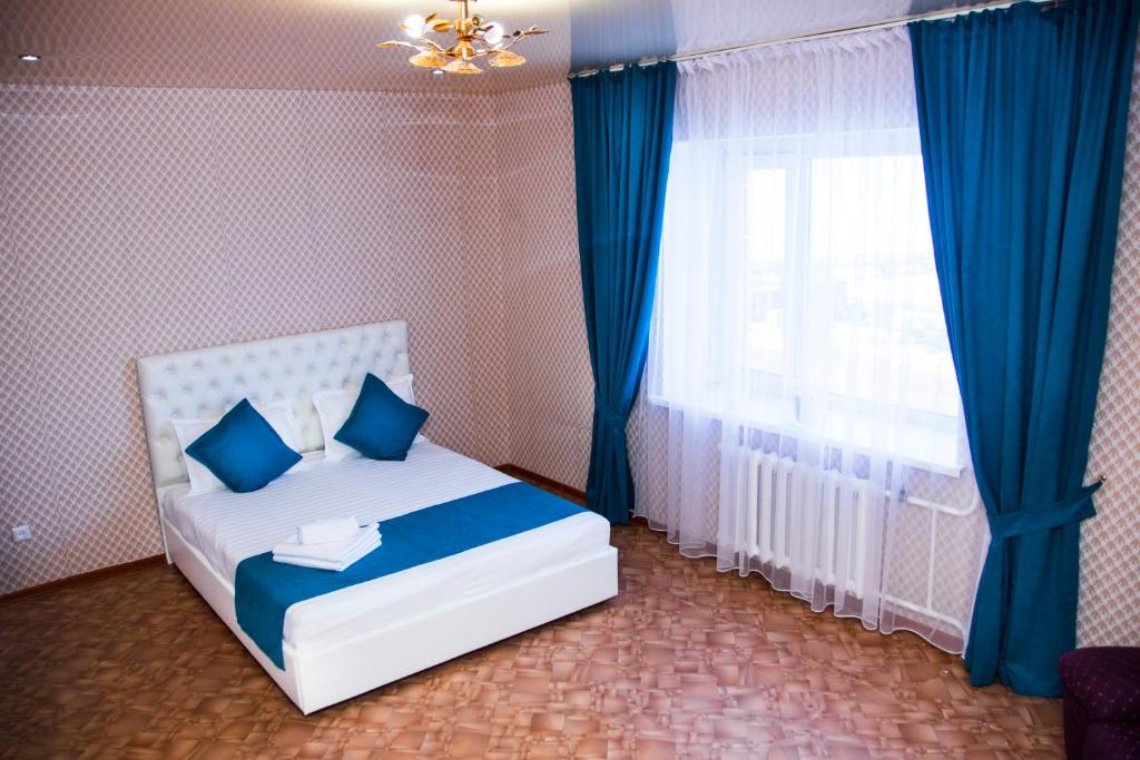 a bedroom with a bed with blue pillows and a window at 1 комнатная квартира, in Kokshetau