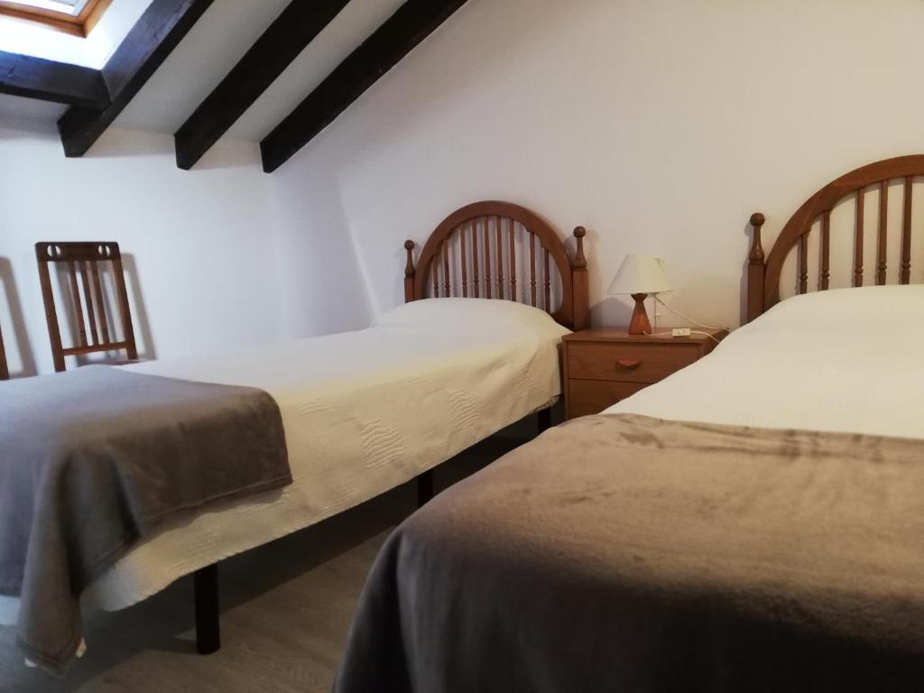 Un dormitorio con dos camas y una mesa con lámpara. en AT Villa Manola, en Colombres