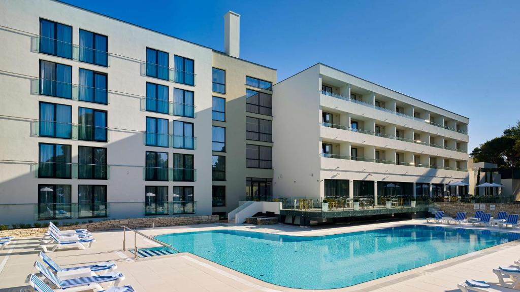 a hotel with a swimming pool in front of a building at Park Plaza Arena Pula in Pula
