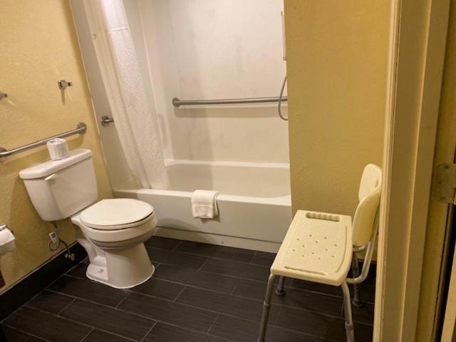 a bathroom with a white toilet and a bath tub at La Casa Inn and Suites in Tallahassee