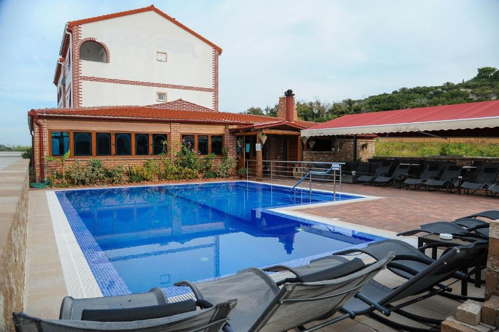 a swimming pool with chairs next to a building at Apartments BRANO - with swimming pool in Novalja